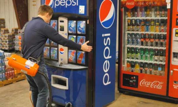 A man using an Airsled vending mover to move a Pepsi machine