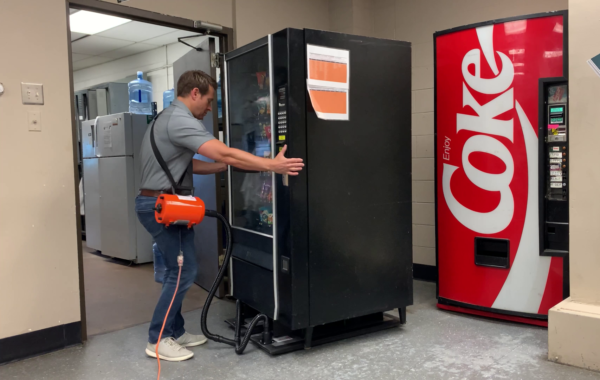A man using a vending mover to move a snack machine